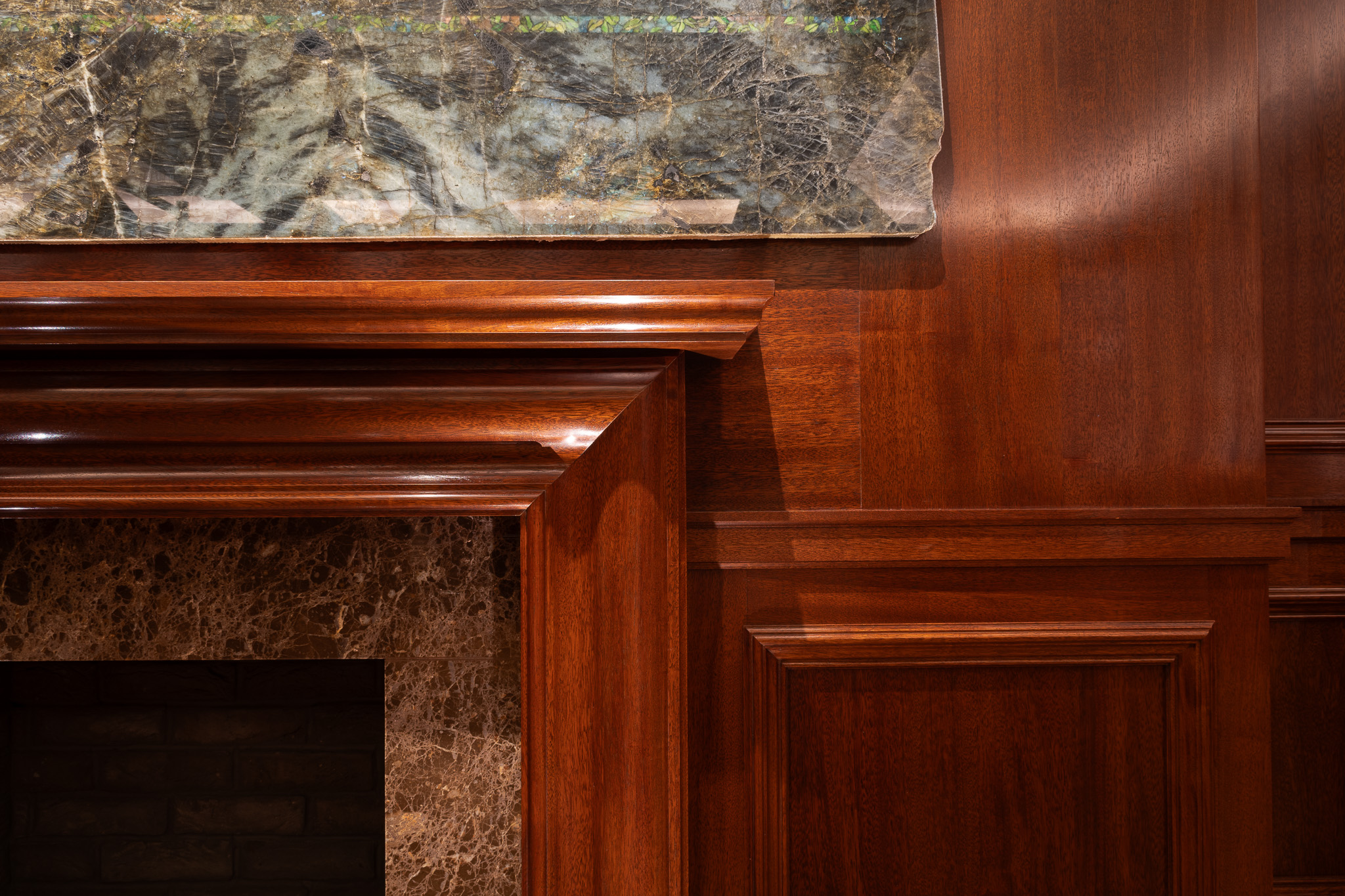 Traditional panelling and fireplace with Bolection moulding in african mahoghany for an entertainment soace and gamnes room in a London home by William Garvey Bespoke furniture maker and designer