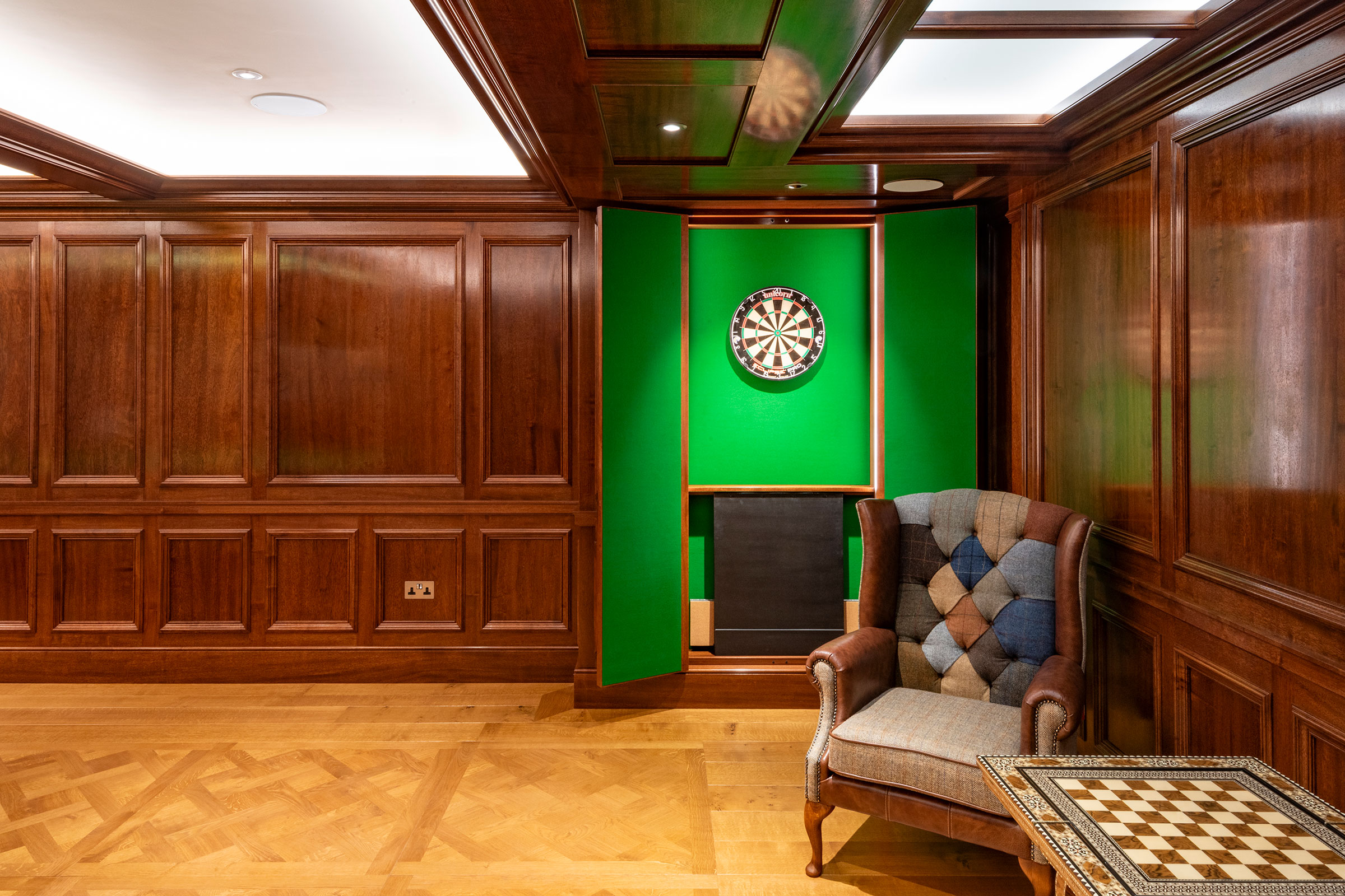 Dartboard cupboard and traditional panelling in african mahoghany for an entertainment space and games room in a London home by William Garvey Bespoke furniture maker and designer