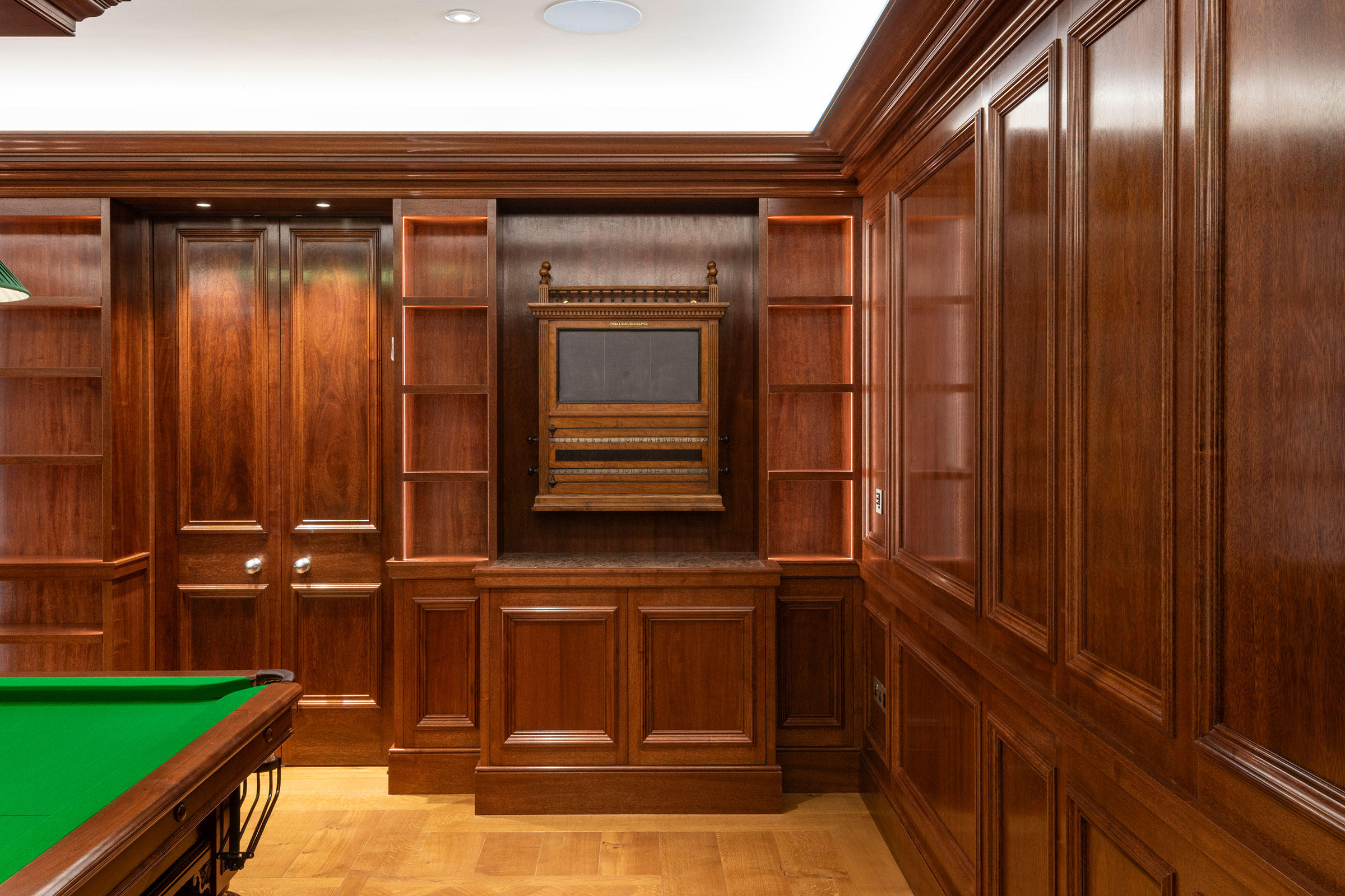 Snooker scoreboard cupboard and traditional panelling in african mahoghany for an entertainment space and games room in a London home by William Garvey Bespoke furniture maker and designer