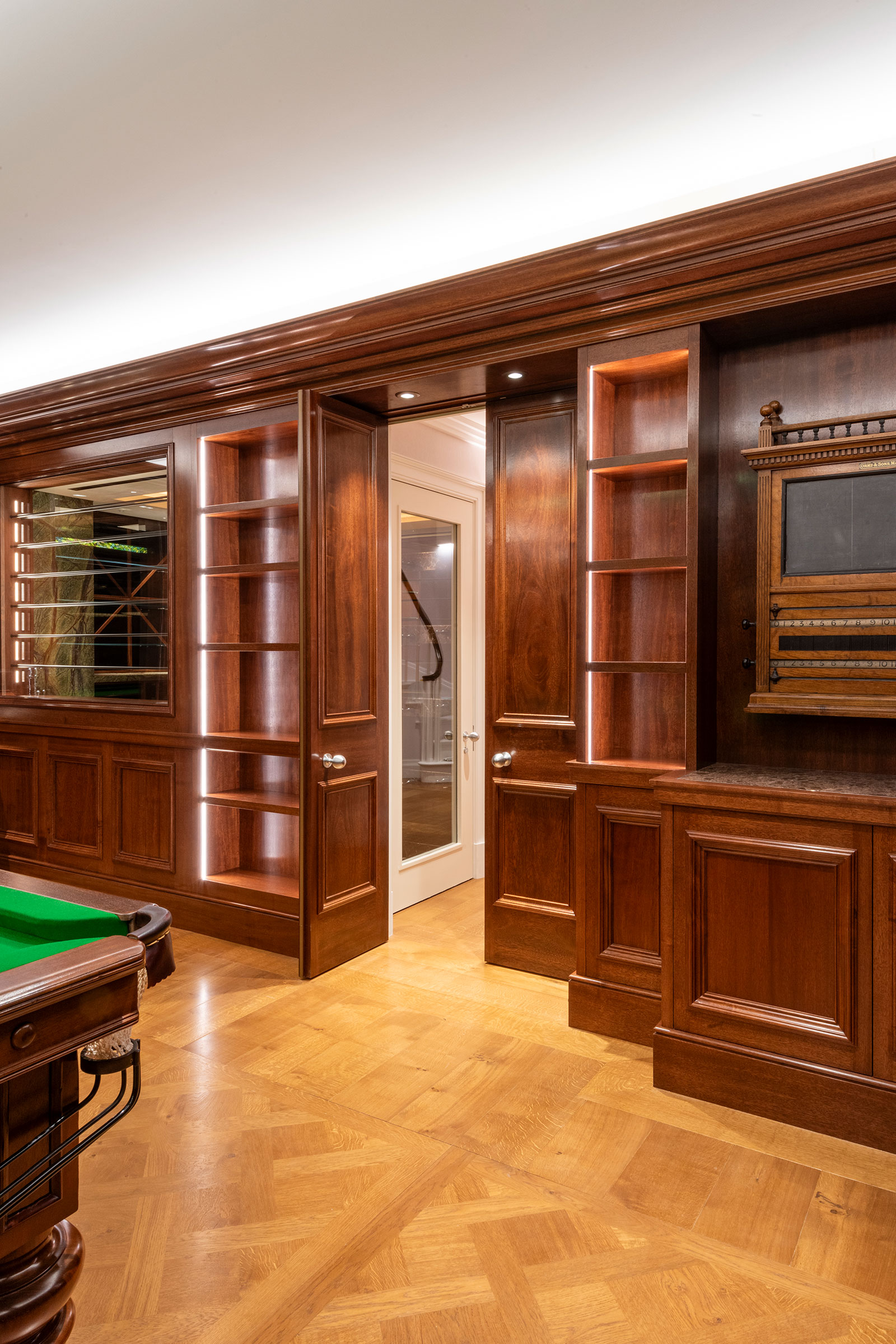 Traditional panelling and shelving in african mahoghany for an entertainment space and games room in a London home by William Garvey Bespoke furniture maker and designer