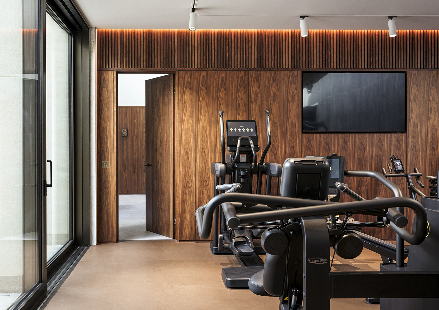 Bespoke walnut wall panelling and doors in the gym and wellness suite of a listed manor house in Somerset - all bespoke joinery and furniture by William Garvey British furniture designers and makers